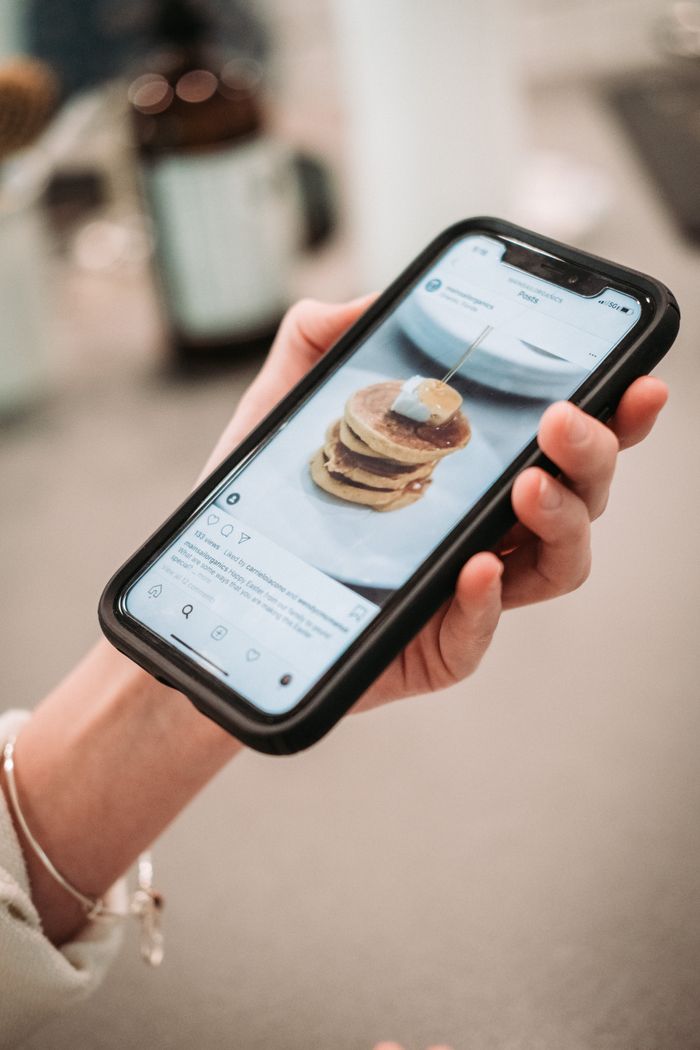 Mastering the First Impression: Your intriguing post title goes here Hand holding a smartphone displaying a pancake recipe on a social media app.
