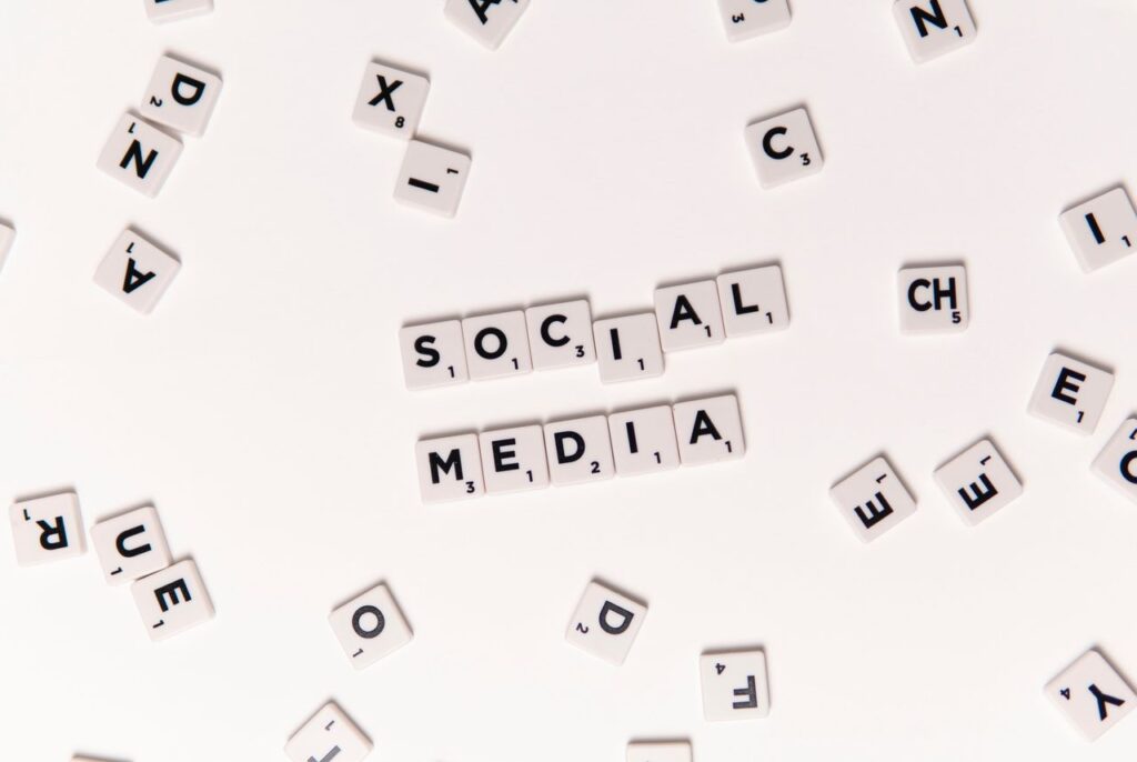 Flat lay of letter tiles spelling Social Media with scattered white tiles on a surface.